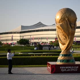 A man takes a picture of a FIFA World Cup trophy replica in front of the Al-Bayt Stadium in al-Khor on November 10, 2022, ahead of the Qatar 2022 FIFA World Cup football tournament. (Photo by Kirill KUDRYAVTSEV / AFP) (Photo by KIRILL KUDRYAVTSEV/AFP via Getty Images)