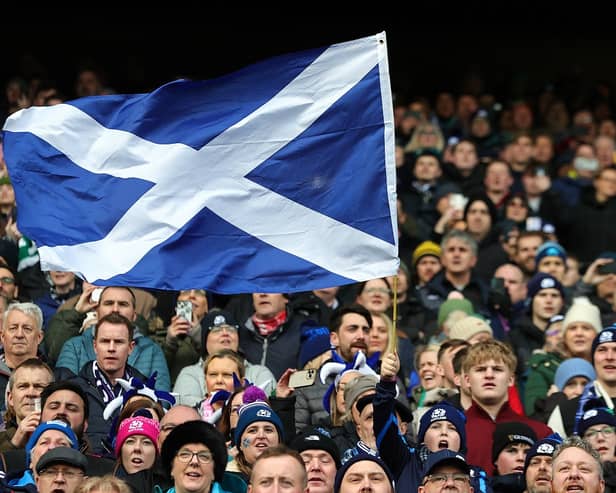 A Scotland fan waves a national flag as they enjoy the pre-match atmosphere prior to a Six Nations Rugby match at Murrayfield Stadium