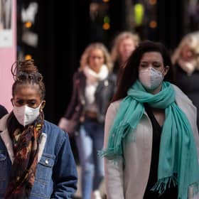 A woman wears a face mask while walking on Oxford Street.