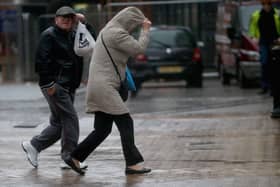 People walk in rain and high winds.
