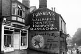 Shops on Stonegate Road in August 1953. Nancy Kirby ladies hairdresser and Franklin's wallpaper, paints, etc. shown. Beckett Arms pub is on the corner with Meanwood Road in the background. Advertisement for Zip dry cleaning on side of shop.