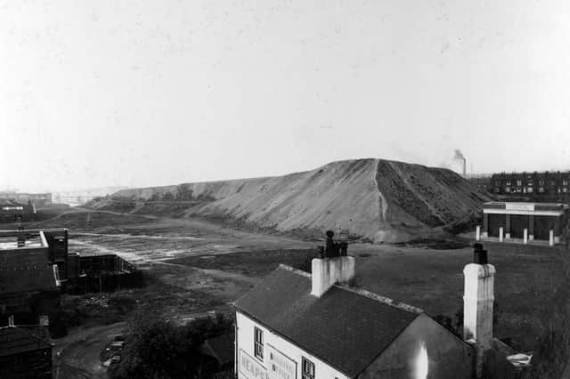The Pit Hills on York Road pictured in September 1938. Buildings to left, pit hills in the foreground. At the foot of the picture is 'John William Heaps' - a two storey building with the sign on the front saying 'Heaps Motor Booking Office'