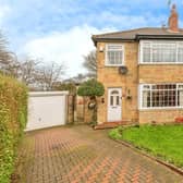 To the front of this three-bedroom home is a small lawned garden and a large driveway leading to a garage.