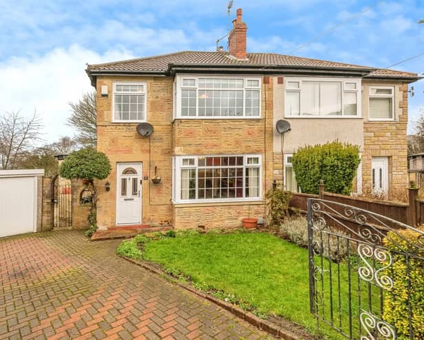 To the front of this three-bedroom home is a small lawned garden and a large driveway leading to a garage.