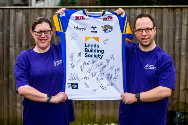 Sally Gutteridge, 49, with husband Jon Gutteridge, 42, holding up a signed Leeds Rhinos shirt which will be raffled for charity. Photo: James Hardisty 