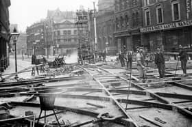 The junction of Briggate and Boar Lane during the relaying of tram tracks in 1899. The tracks were made at Hunslet Steel Works and laid out in a network. The spaces were filled with end grain wood blocks in this particular area instead of the usual stone setts in an effort to reduce noise. In the background is the spire of the Holy Trinity Church.