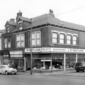 Beeston Road in October 1963. The shops on Beeston Hill including at number 101 (just visible) Marsh Jones & Cribb Ltd, painting contractors. At number 103 is a grocers advertising cigarettes and Typhoo Tea. On the right at numbers 105 & 107 is V.W. Pratt & Son, house furnishers and upholstery. Advertised in the window are 'The latest designs always on show'. On the right cars including the Una Street while more cars are parked on Beeston Road.
