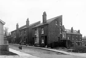 Raby Mount, seen from Sheepscar Street. Just seen on the left edge is the wall of a new Police Section House. At the end of Raby Mount, premises belonging to G.W. Binns, motor garages are visible. Raby Mount at this point comprised 3 pairs of houses. On the right is Yeomanry Street. Pictured in May 1958