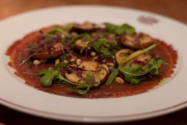 Carpaccio di Manzo - beef carpaccio served with parmesan whip, fresh porcini, caper and parsley dressing, pine nuts and olive (Photo by San Carlo)