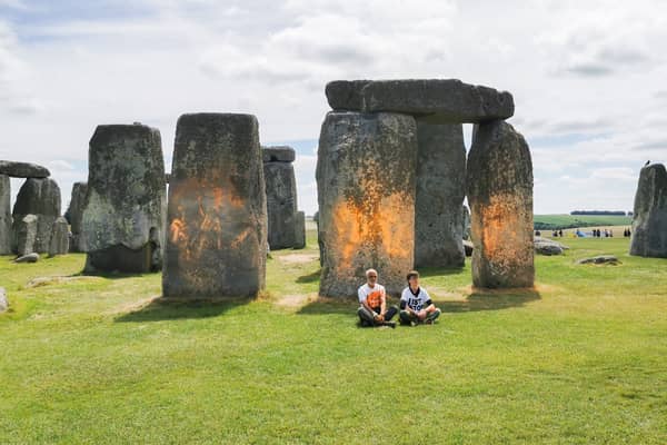 Activists sitting by Stonehenge after it was sprayed orange (Photo: Just Stop Oil / Supplied)