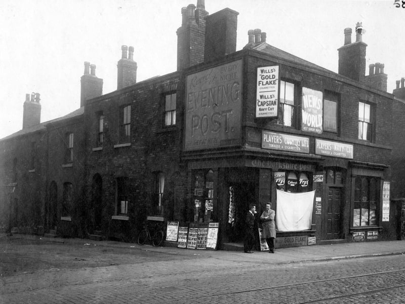 Highgate Street at the junction with Low Road in September 1929. On the corner is the premises of newsagent John Normington. The shop has painted sign for 'Evening Post' newspaper on wall, metal sign for 'News of the World' Sunday newspaper. Advertisements for tobacco including Will and Players Cigarettes. A blind is over the shop window and to the side, placards with news headlines. Number 9, shop premises of John Benson Hardaker, shoe and boot repairer.