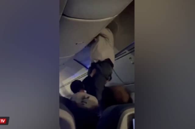 Passengers help man from overhead bin after 'strong turbulence'.