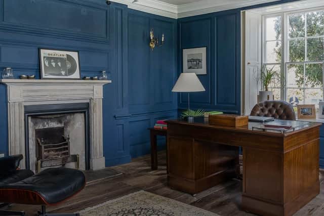 The cosy study features wood panels on the walls