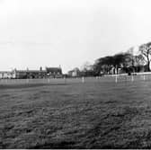 Looking North-West across The Green towards The Cricketer's Arms, which has a sign for John Smith's Magnet Ales on it. Seacroft Grange C.P. School is just visible on the far right. The Green's cricket pitch is roped off. Pictured in October 1954.