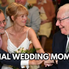 A couple on their wedding day clasping hands with the bride's father
