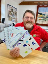David at Lineham Farm holding thank you cards from a Leeds school after their visit.