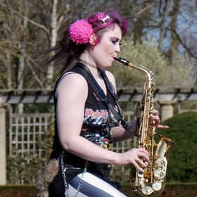 Rachel Ward unicycling while playing the saxophone
