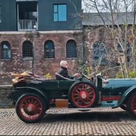 An antique car driving down a cobbled street