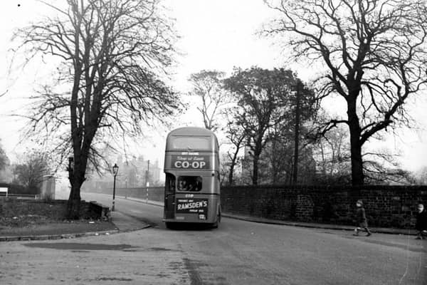 Looking east at the junction of Kirkstall Lane and Queenswood Drive. A bus for City Square drives away with advertisements for Leeds Co-op and Ramsdens. Two boys cross the road on the right. Pictured in October 1949.