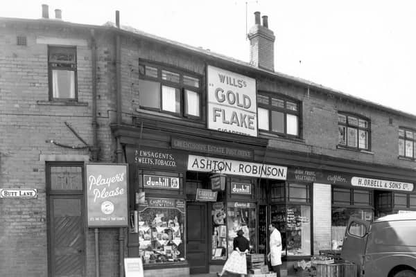 The west side of Butt Lane at the corner of Pudsey Road in May 1956. At number 2 Butt Lane is 'Ashton. Robinson, shopkeeper'. At number 203 Pudsey Road is 'H. Orbell & Sons Ltd, outfitters'.