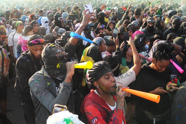 Revellers blow horns and dance through the streets during the early-morning J'ouvert procession, opening the celebrations in a haze of paint, powder, and sound