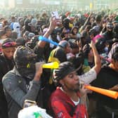 Revellers blow horns and dance through the streets during the early-morning J'ouvert procession, opening the celebrations in a haze of paint, powder, and sound