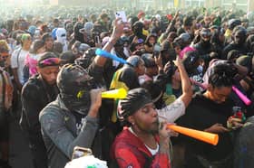 Revellers blow horns and dance through the streets during the early-morning J'ouvert procession, opening the celebrations in a haze of paint, powder, and sound