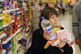 A woman carries her shopping at a branch of Tesco. Essentials like vegetables, milk, eggs, cheese, and fish are driving higher household costs. (Photo: ADRIAN DENNIS/AFP via Getty Images)