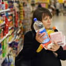 A woman carries her shopping at a branch of Tesco. Essentials like vegetables, milk, eggs, cheese, and fish are driving higher household costs. (Photo: ADRIAN DENNIS/AFP via Getty Images)