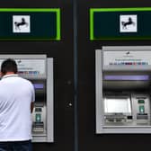 A man takes money from a cash machine at a branch of Lloyds Bank. The banking group will close 49 branches across the UK between January and October 2026 (Photo: Carl Court/Getty Images)