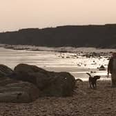 Polly Brown walks her dogs on Hornsea beach in October 1998 against a backdrop of an eroding coastline.