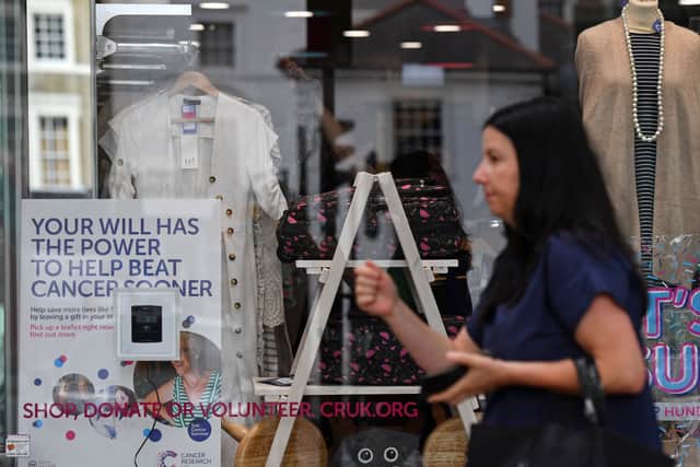 A woman walks past a Cancer Research UK store in London. The charity shop chain will  close 88 high street shops by May 2026, with 100 more expected by April 2027 (Photo: BEN STANSALL/AFP via Getty Images)