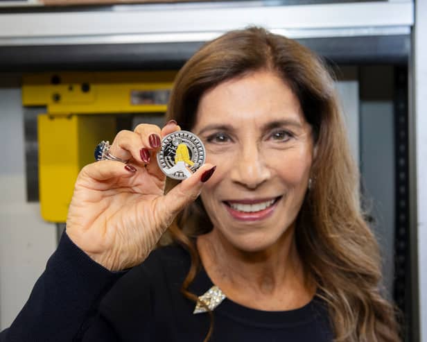 Freddie Mercury's sister, Kashmira Bulsara, holding the new Royal Mint commemorative coin. The design features Mercury mid-performance, his signature, and details like his Live Aid outfit (Photo: Royal Mint)
