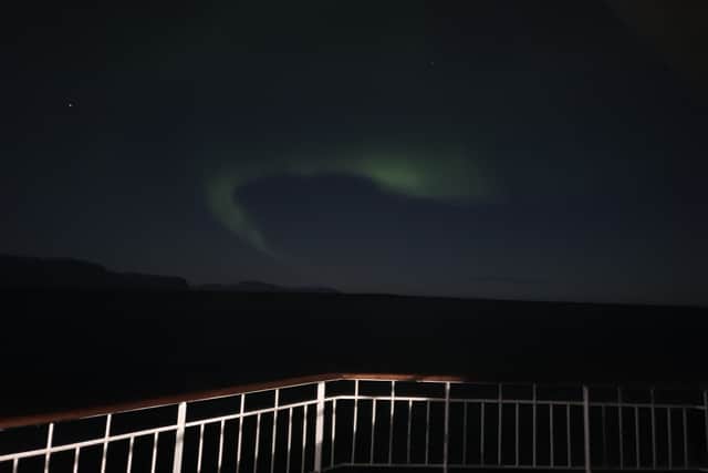 The pale green lights of the aurora borealis dance across the Arctic skies