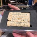 A fragile, century-old "trench biscuit" sent from the First World War front lines in 1914 by Private William Maxwell to his mother in Meanwood. Repurposed as makeshift stationery, it carries a poignant request for "a bit of butter" to accompany his army rations.