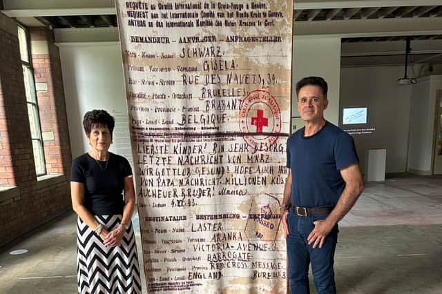 Michelle Green, pictured with her son Joel, stands next to a woven blanket at the Holocaust Centre, bearing the final Red Cross telegram sent by her grandmother.