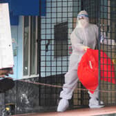 A health worker wearing protective gear disposes of biohazard waste from a Nipah virus isolation centre.