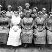  A group of munitions workers and a nurse. The women are wearing protective clothing, munition work was dirty and dangerous.