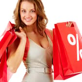A shopper carrying red sale bags marked with a bold percentage sign, symbolising seasonal discounts and bargain hunting