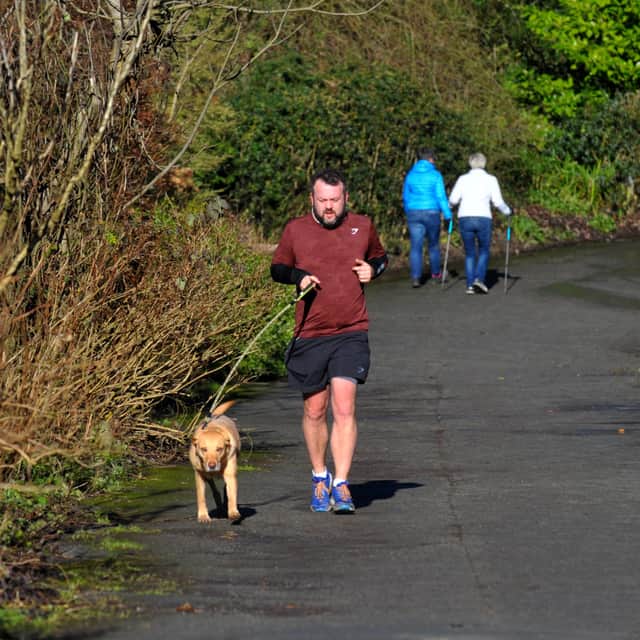 A runner in shorts  in the sun in Golden Acre Park.