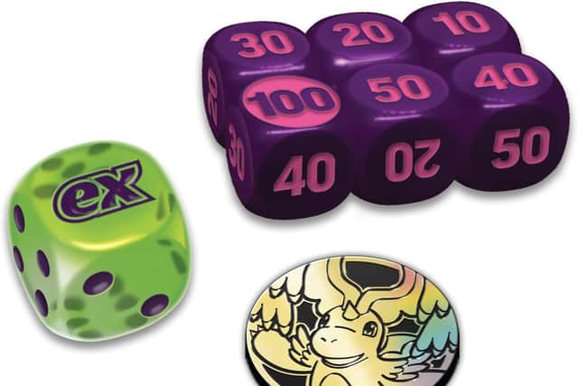 Gameplay accessories include a damage-counter dice, a coin-flip die and a collectible Dragonite Pokémon TCG coin