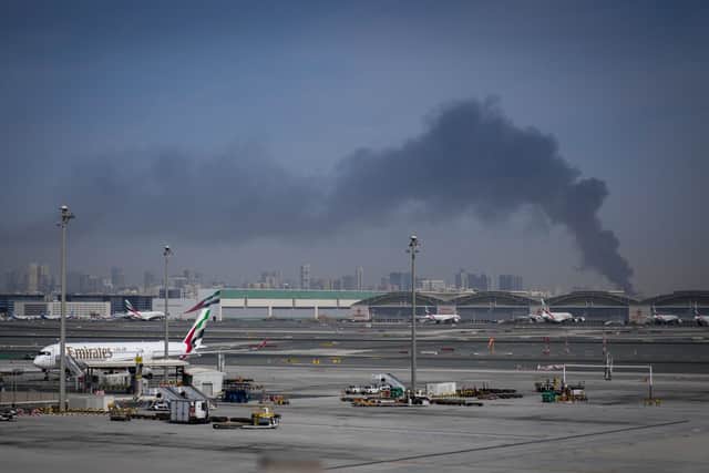 A plume of smoke caused by an Iranian strike is seen as Emirates planes are parked at Dubai International Airport after its closure.
