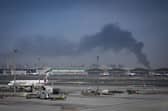 A plume of smoke caused by an Iranian strike is seen as Emirates planes are parked at Dubai International Airport after its closure.