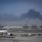 A plume of smoke caused by an Iranian strike is seen as Emirates planes are parked at Dubai International Airport after its closure.