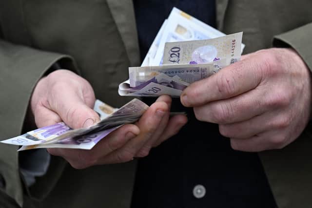 A man handles a wad of £20 notes. Universal Credit payments are set to rise from April, affecting 8.3 million claimants (Photo: PAUL ELLIS/AFP via Getty Images)