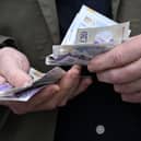 A man handles a wad of £20 notes. Universal Credit payments are set to rise from April, affecting 8.3 million claimants (Photo: PAUL ELLIS/AFP via Getty Images)