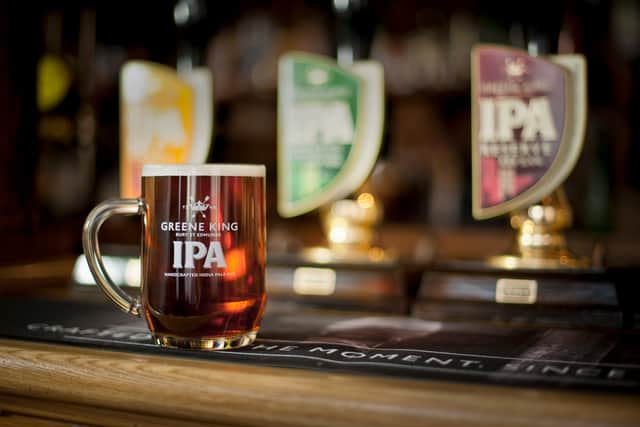 A pint of beer on a bar in front of three beer taps. Greene King is considering putting up to 150 of its managed sites up for sale as part of a shake-up of its estate (Photo: Greene King/PA Wire)