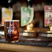 A pint of beer on a bar in front of three beer taps. Greene King is considering putting up to 150 of its managed sites up for sale as part of a shake-up of its estate (Photo: Greene King/PA Wire)