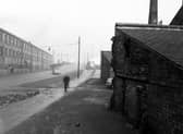 Looking north down Balm Road from the entrance to Robinson's scrap metal yard in December 1951. A car is parked in the entrance, where a man is walking past. On the other side of the road are factory premises.