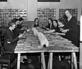 Women sat around a large table preparing the first ration books in November 1939.